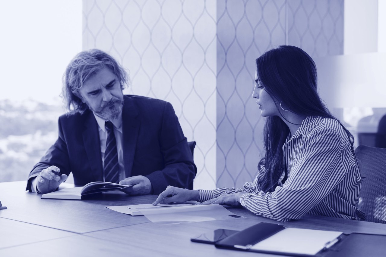 Asesor y cliente revisando juntos un expediente en el despacho